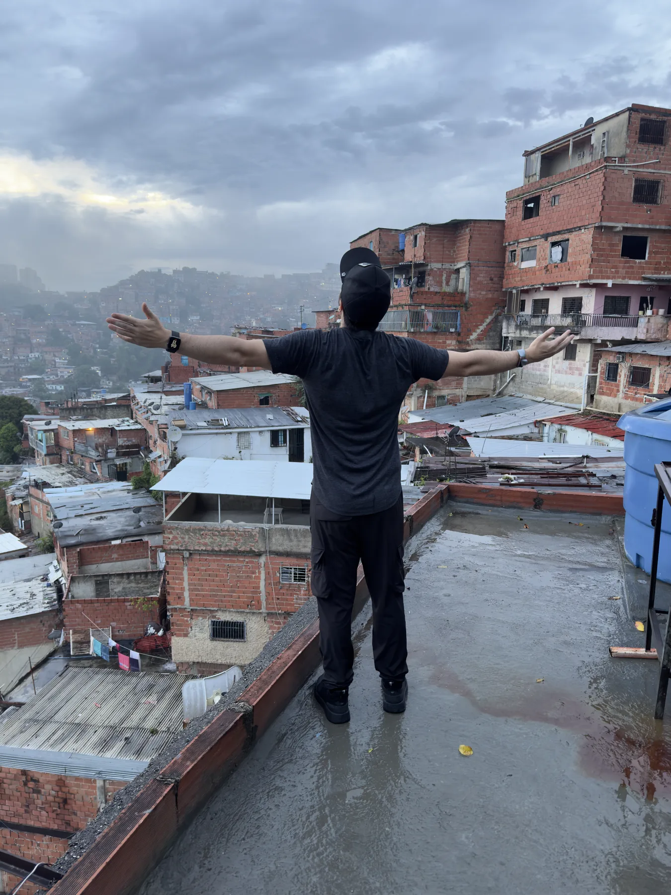 Navid Moazzez with his arms wide on a rooftop in Petare, Caracas