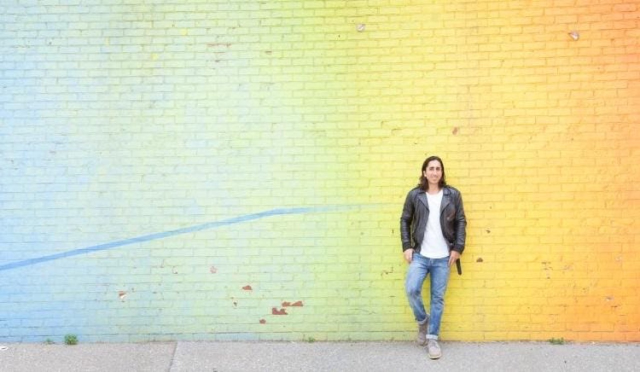 Navid Moazzez in front of a painted brick wall